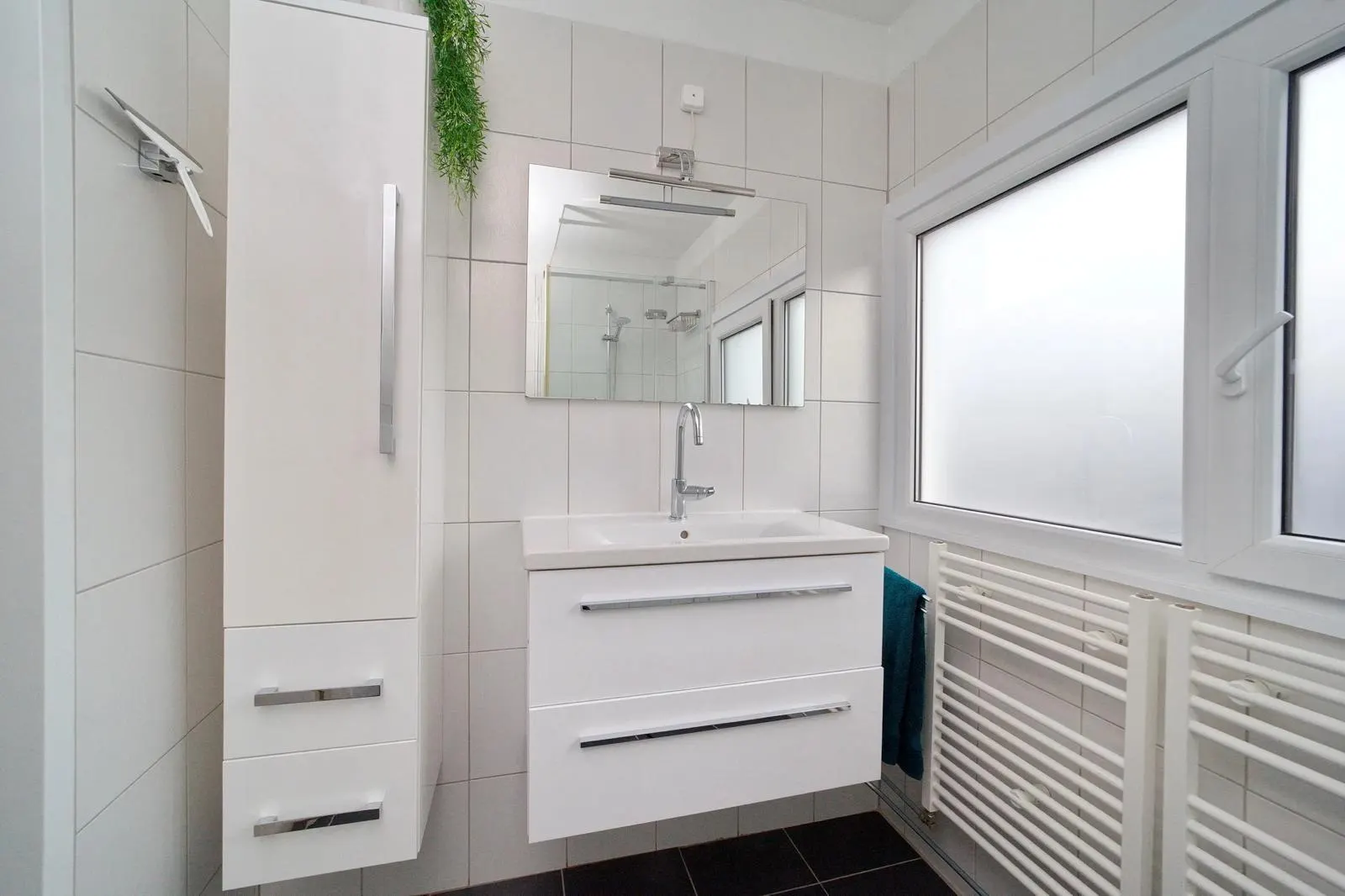 Witte badkamer met wit badmeubel, hoge kast en raam met matglas